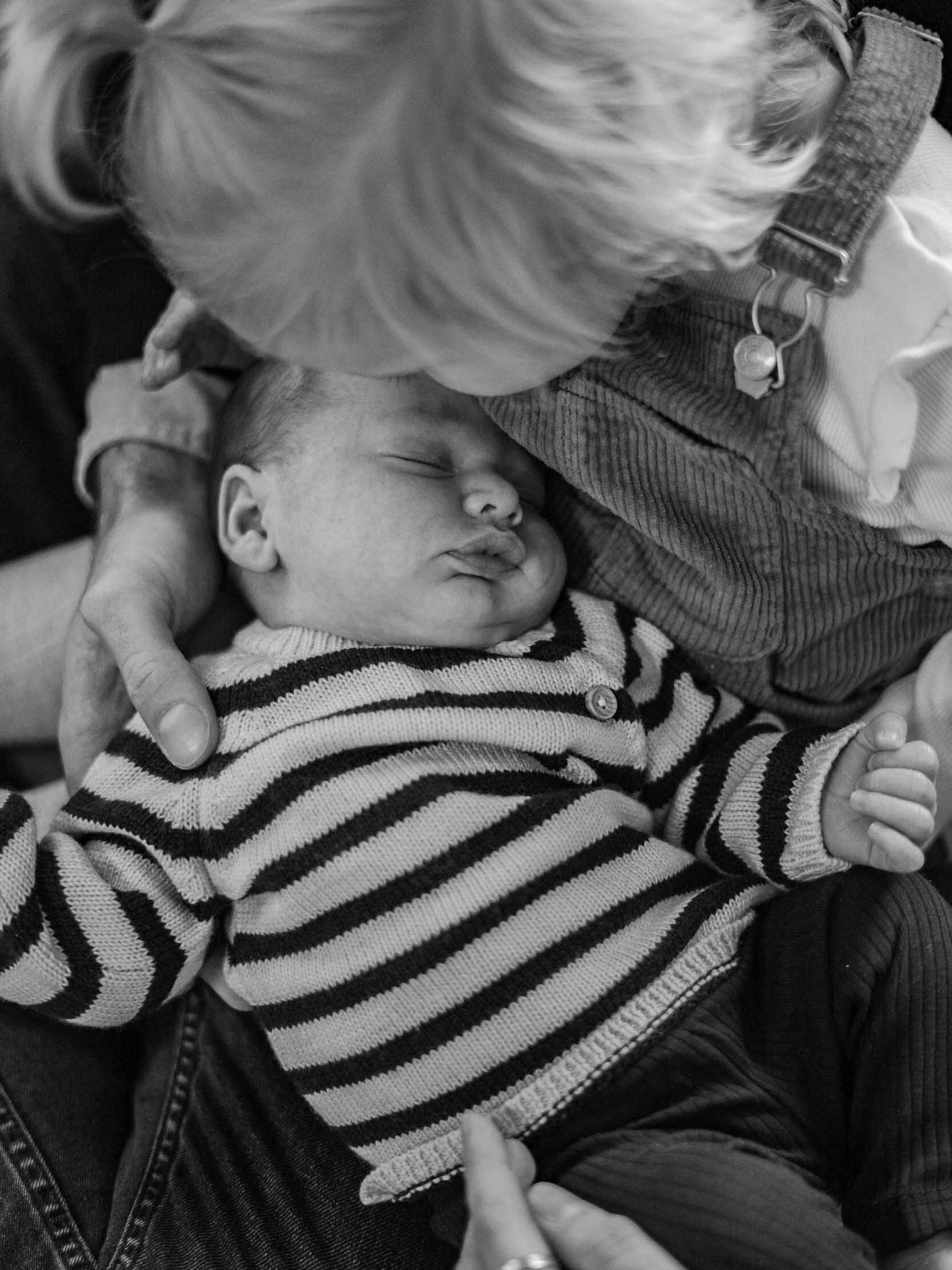 Kleines Baby liegt in den Armen von der kleinen Schwester