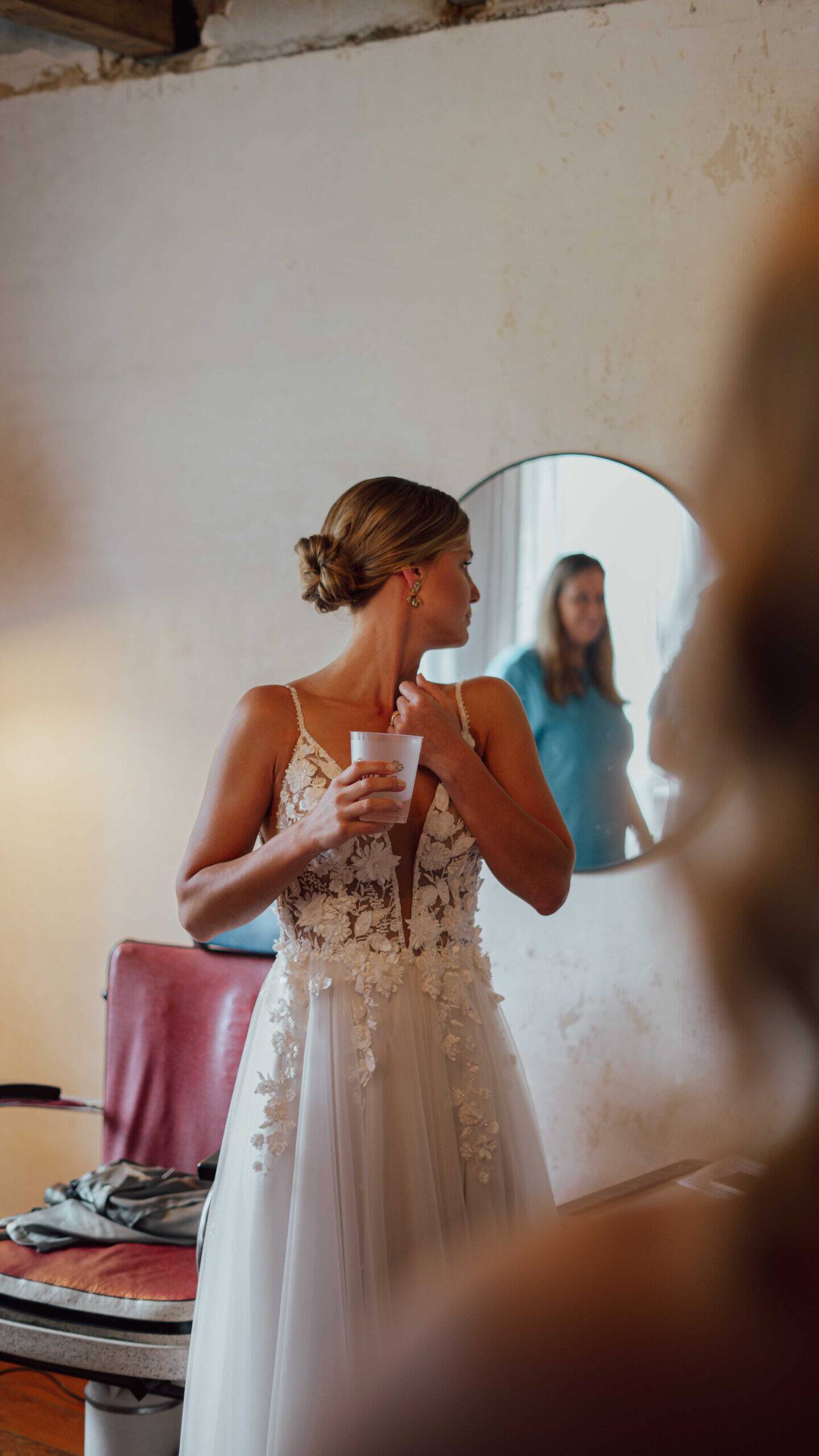 Braut im Hochzeitskleid schaut sich im Spiegel an